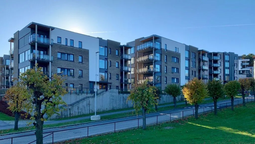 Moderne leilighetsbygg med flere etasjer, balkonger og grøntområde i forgrunnen.